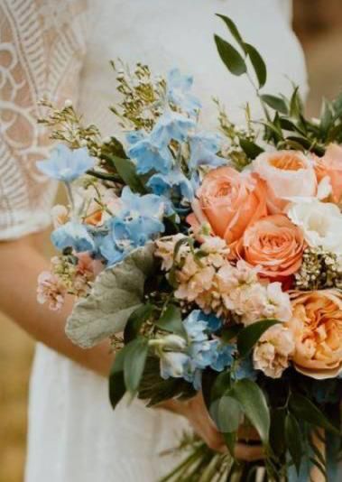Una donna vestita di bianco tiene in mano un mazzo di fiori.