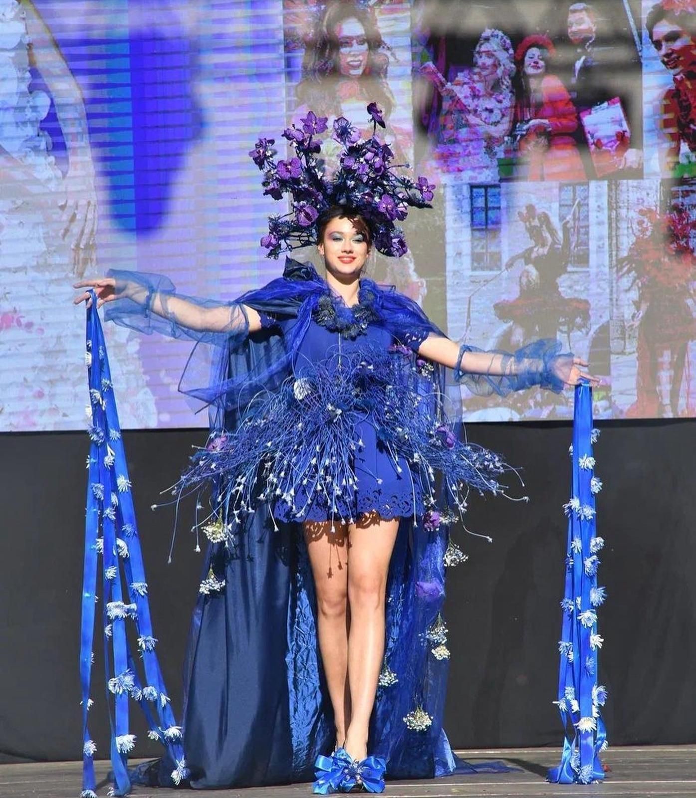 Una donna con un vestito blu con fiori viola in testa