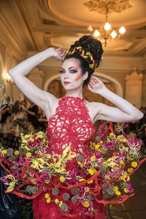 A woman is wearing a red dress made of flowers.