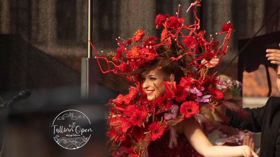 A woman is wearing a hat made of red flowers.