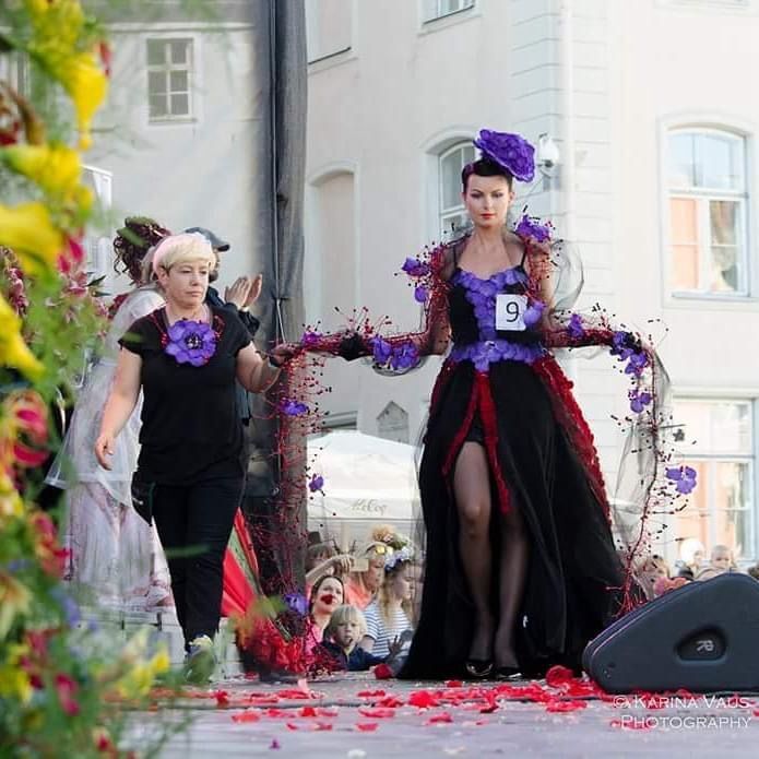 Una donna con un vestito nero con fiori viola ha il numero 9 sulla manica