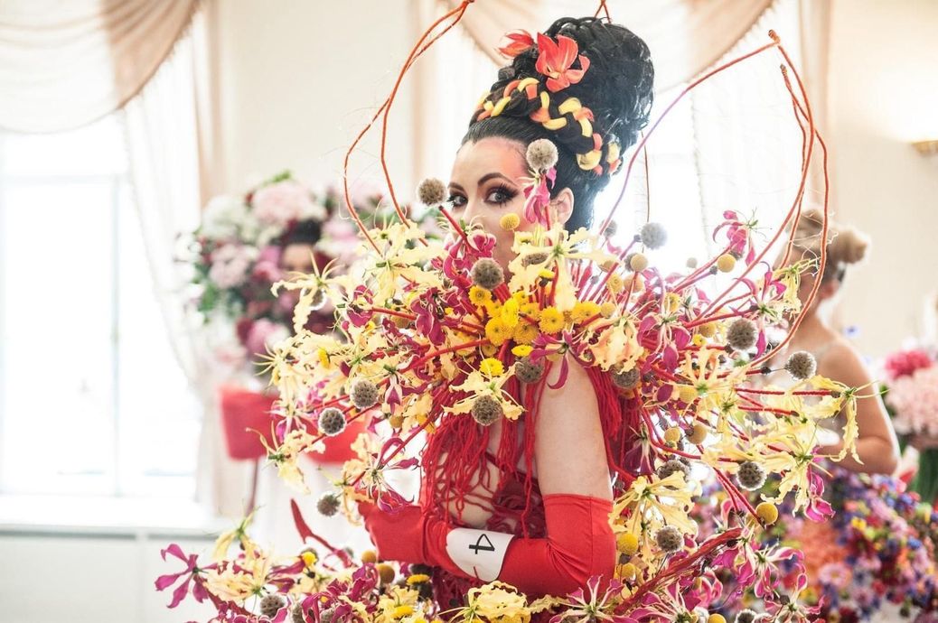 A woman in a red dress is covered in flowers.