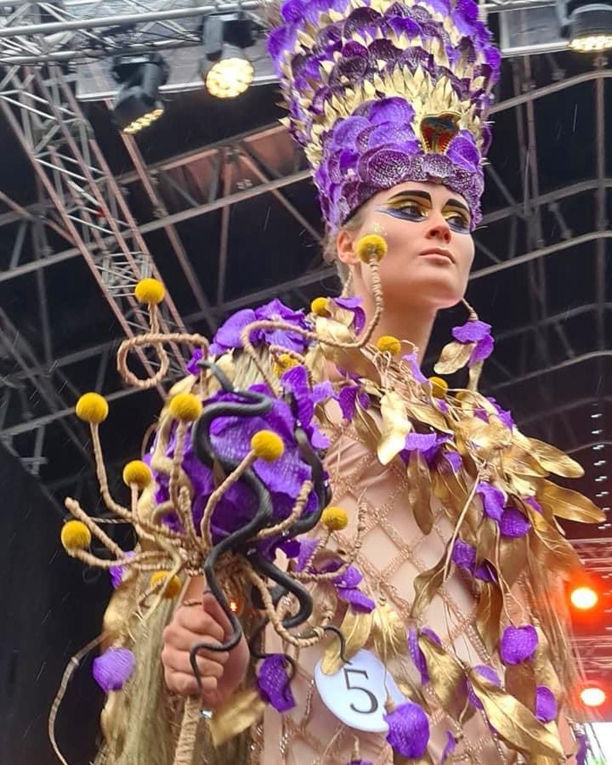 Una donna in costume viola e oro con il numero 5 sul braccio