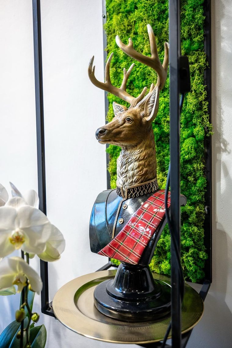 Su un tavolo è seduta la statua di un cervo che indossa un kilt.