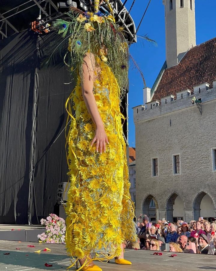 A woman in a yellow dress is standing on a stage in front of a crowd.
