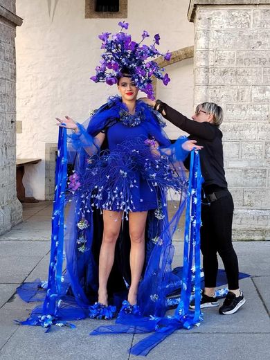 A woman with a blue dress with purple flowers on her head