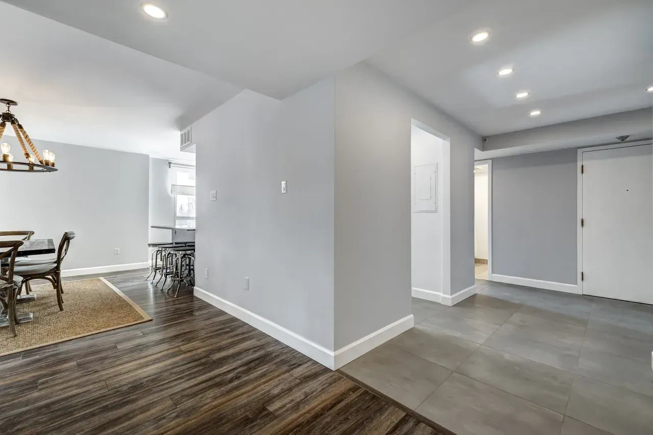 A hallway in a house with a wooden floor and a chandelier.