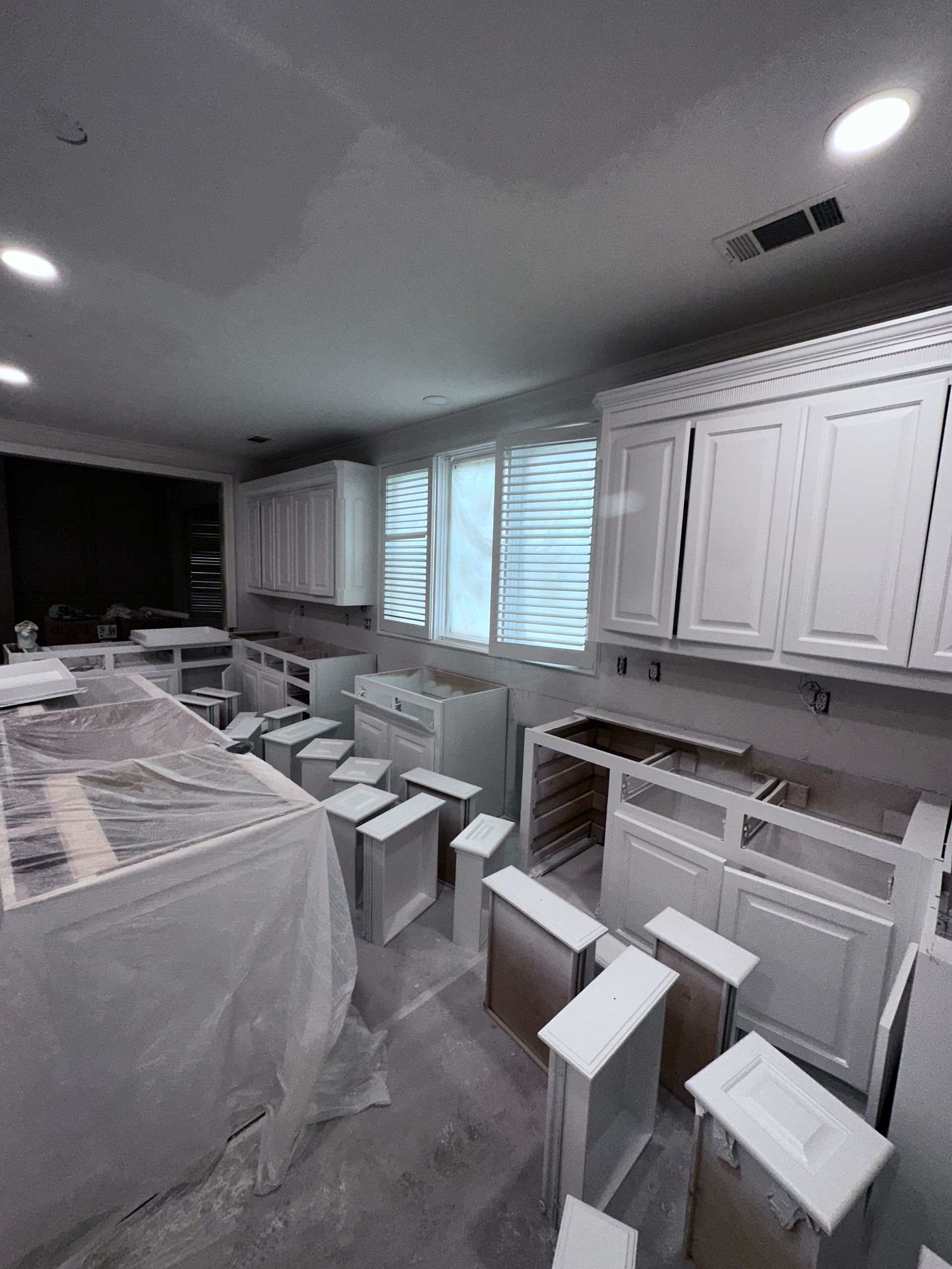 A kitchen with white cabinets and drawers is being painted.