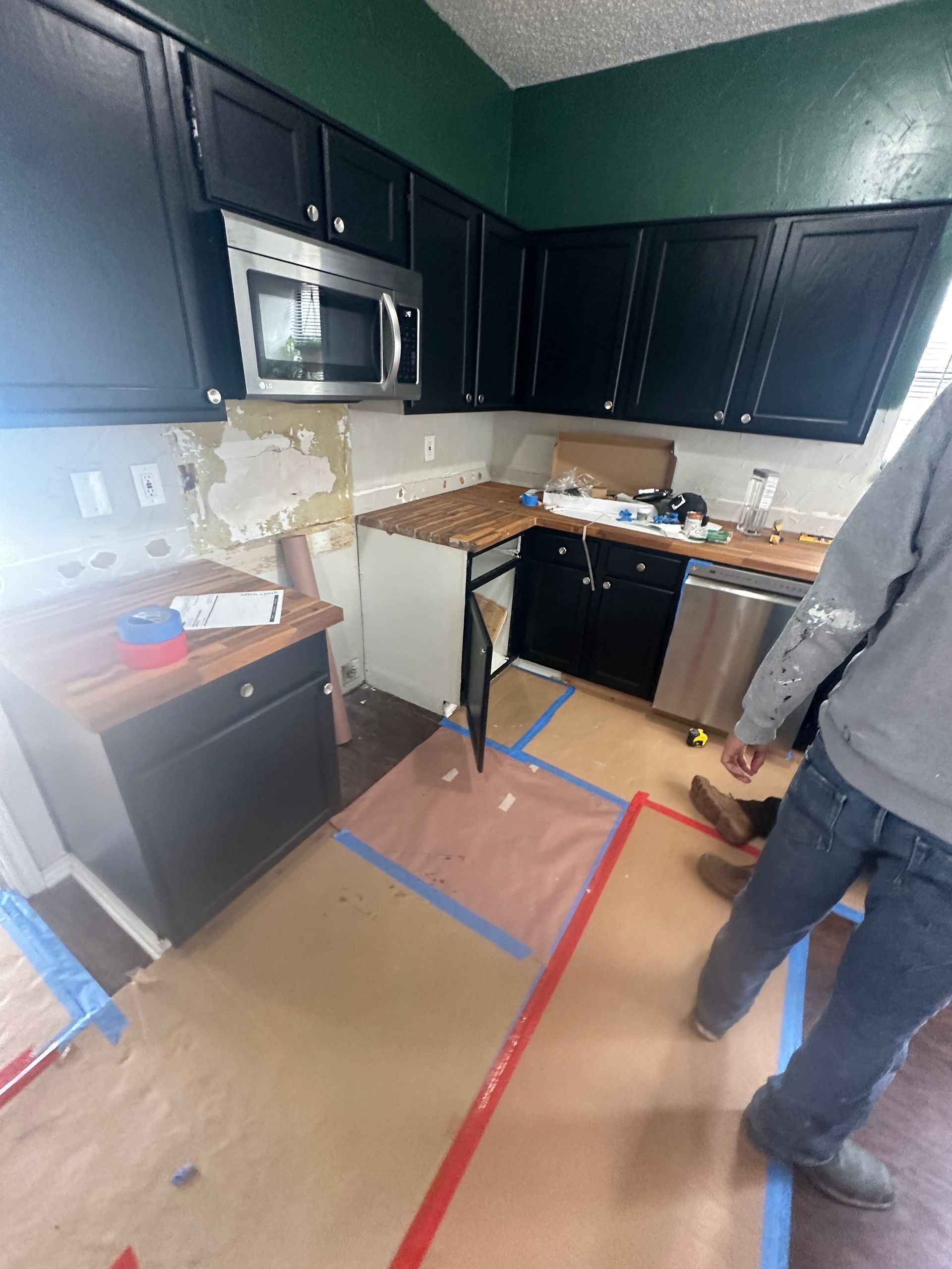 A kitchen with black cabinets and stainless steel appliances is being remodeled.