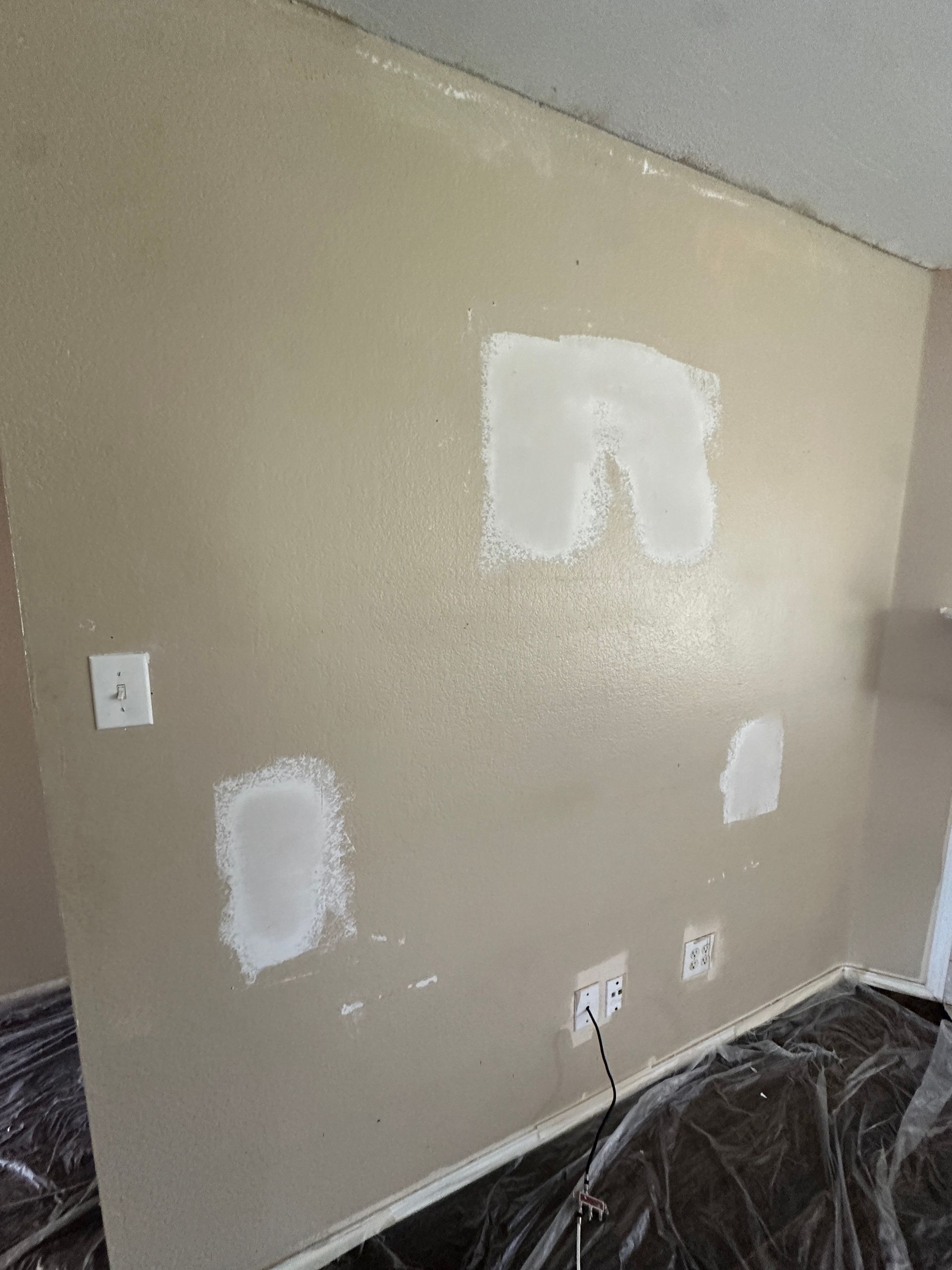 A room with a wall that is being painted and plastered.