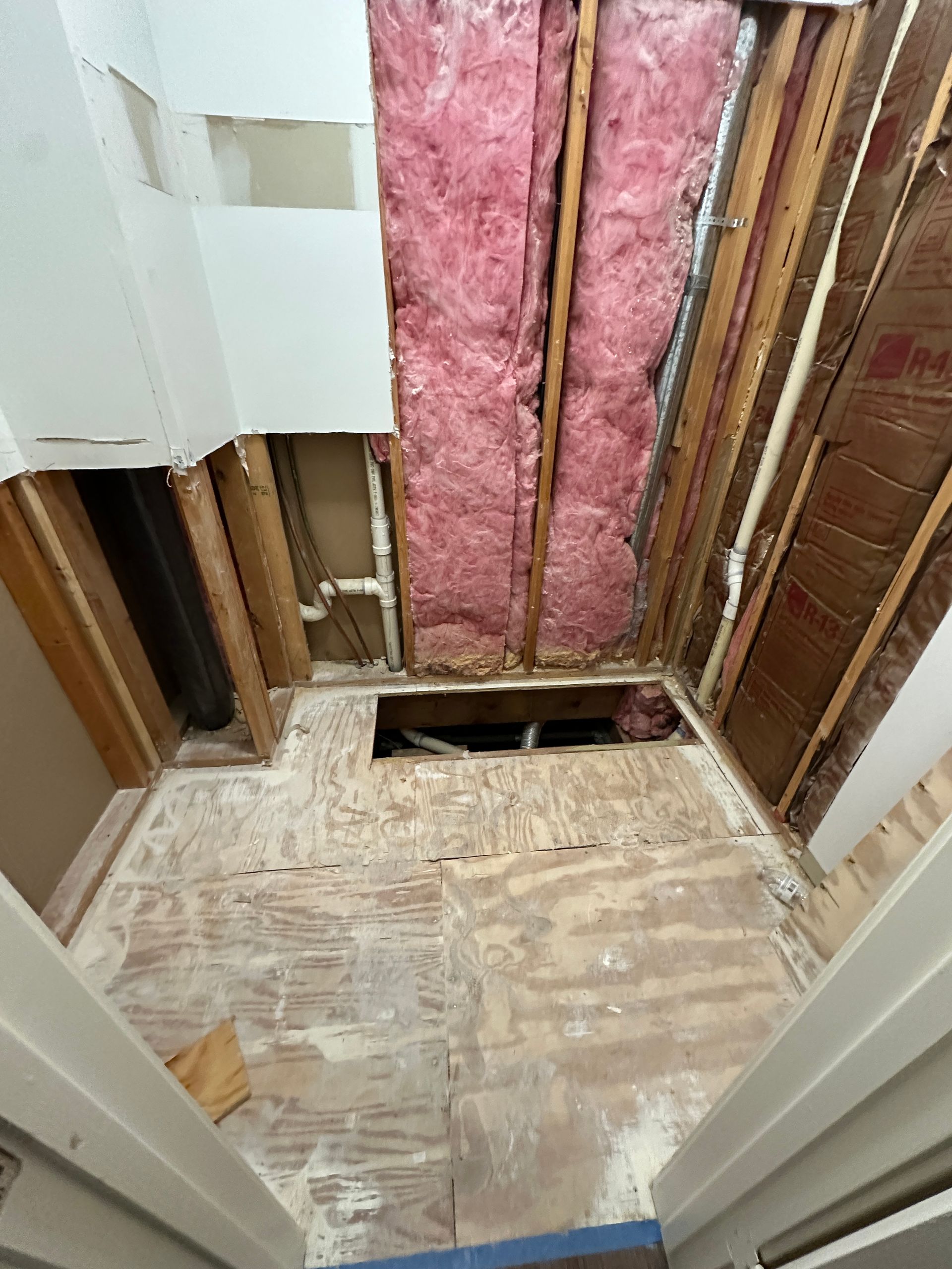 A room with a hole in the ceiling and pink insulation.