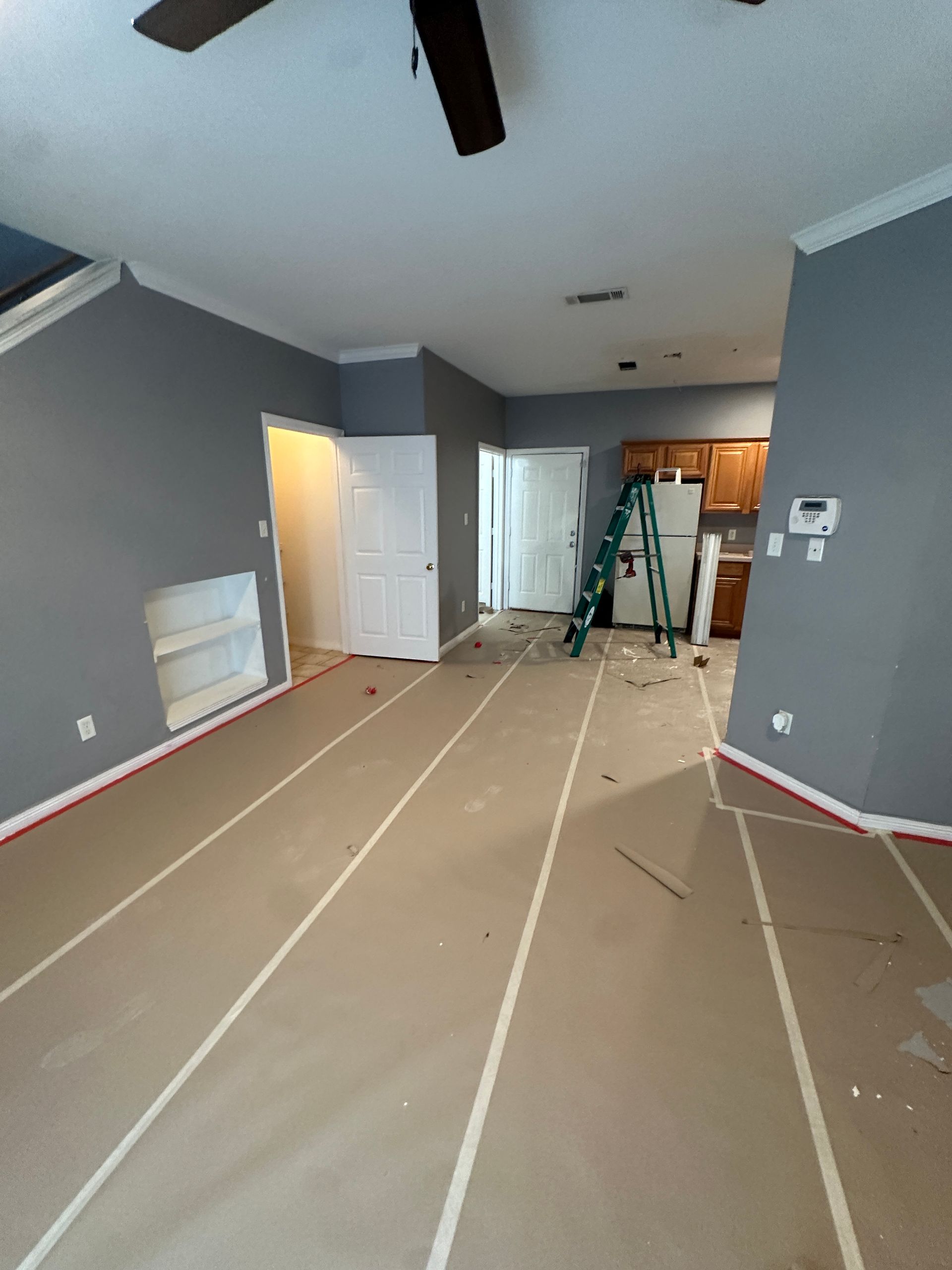 An empty room with a ladder and a ceiling fan