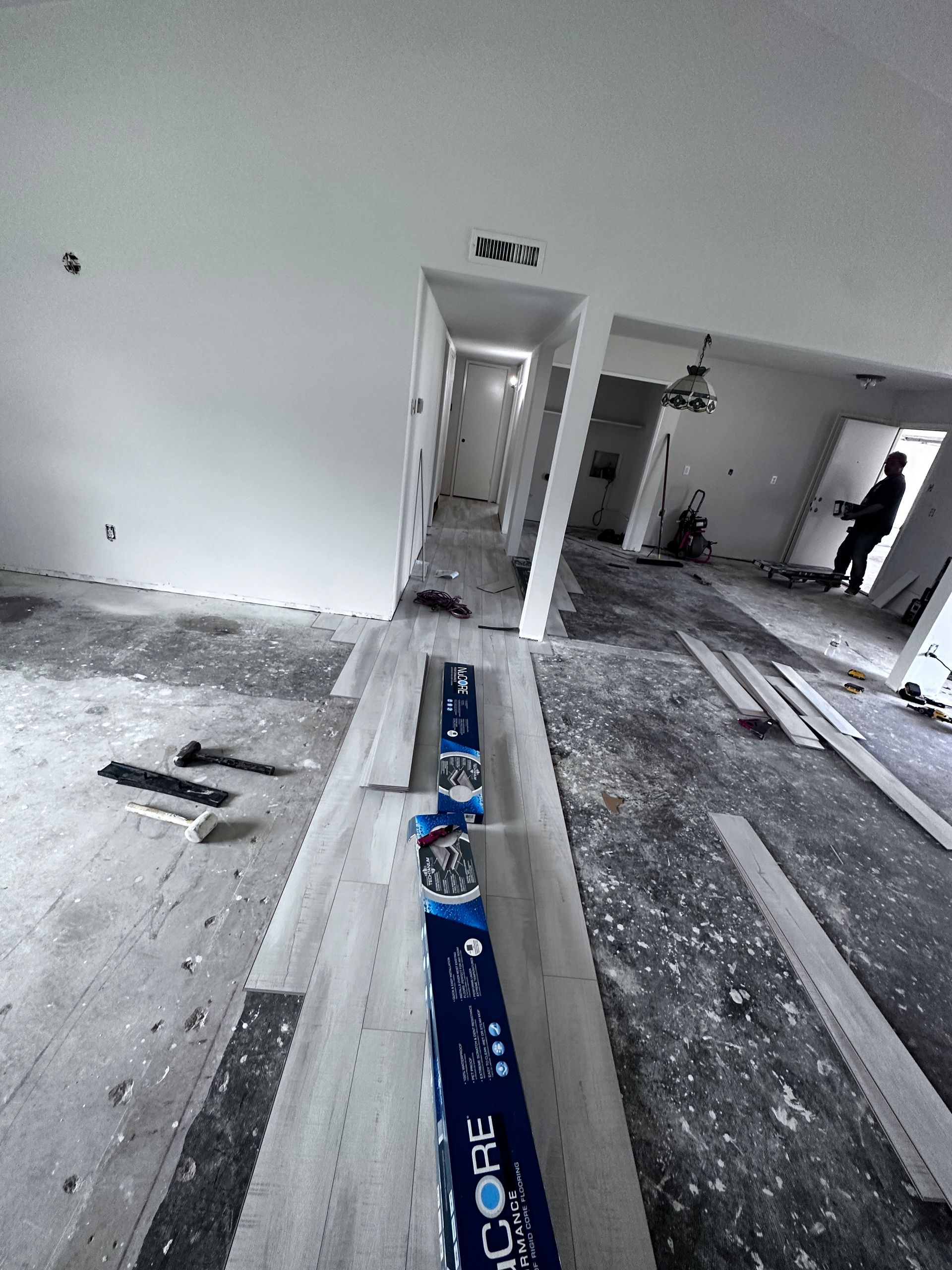 A person is standing in a room with a box of oreos on the floor.