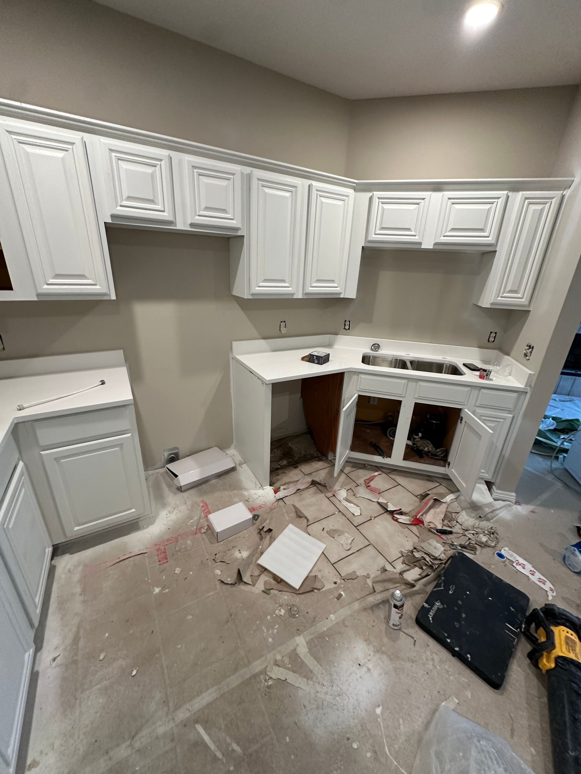 A kitchen with white cabinets and a sink is being remodeled.