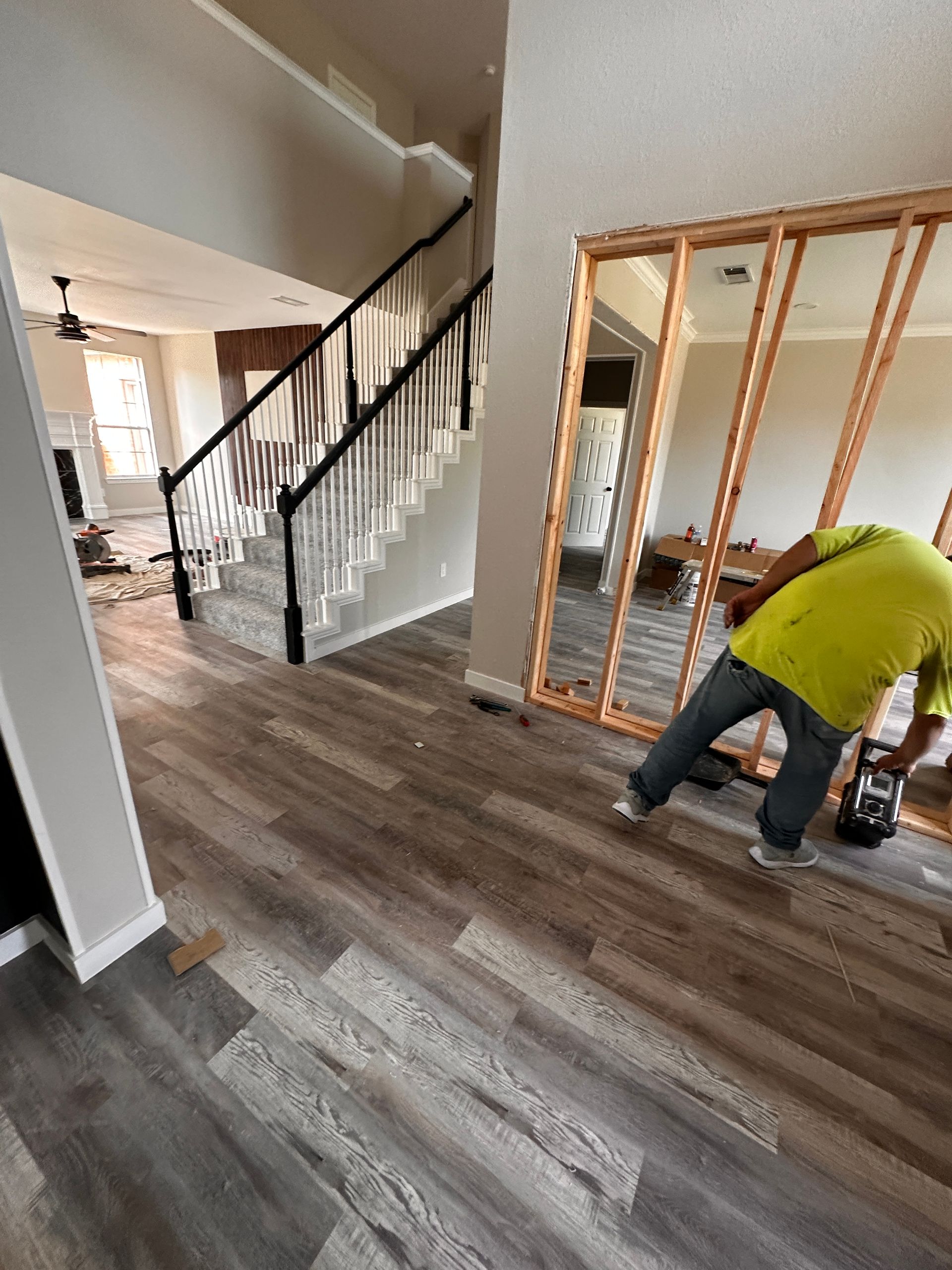 A man is working on a wooden floor in a living room.