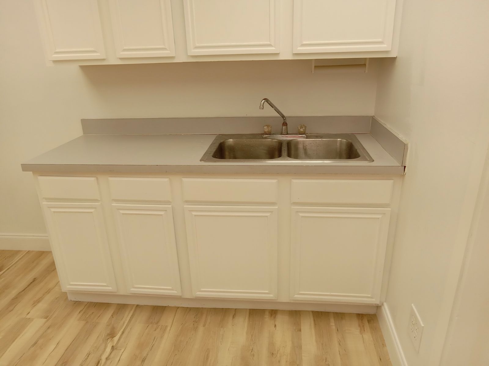 A kitchen with white cabinets and a double sink.