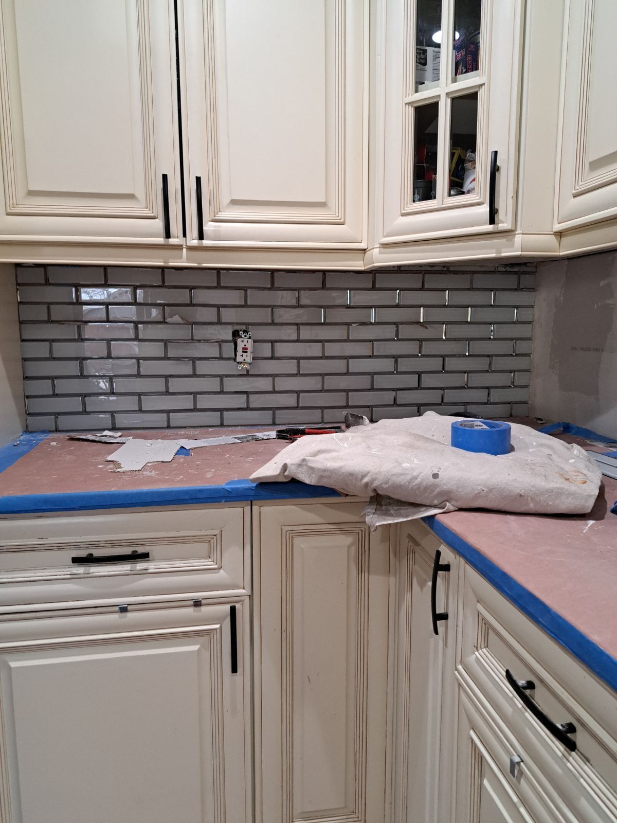 A kitchen with white cabinets and blue tape on the counter.