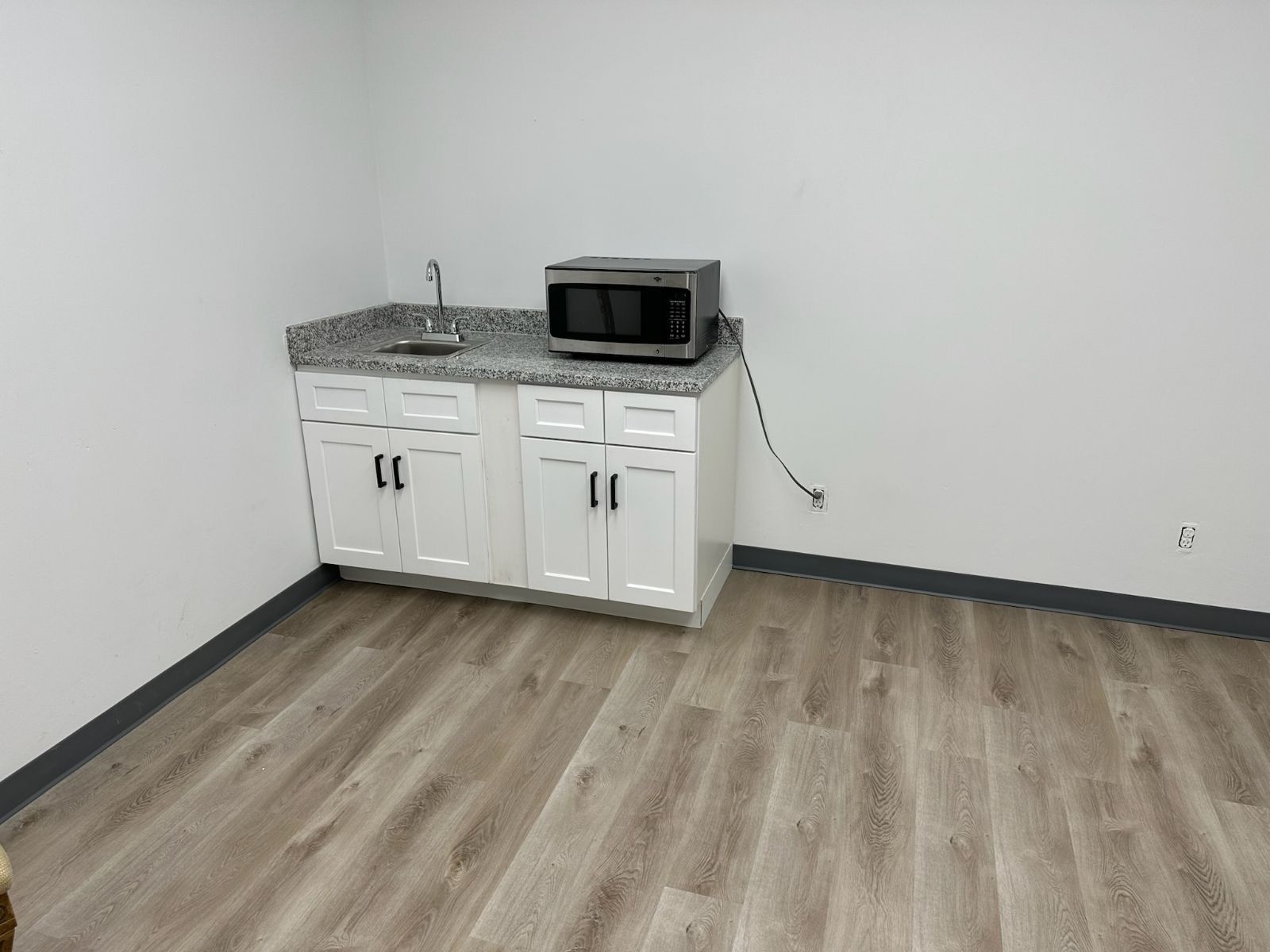 A kitchen with a sink , microwave , and cabinets.
