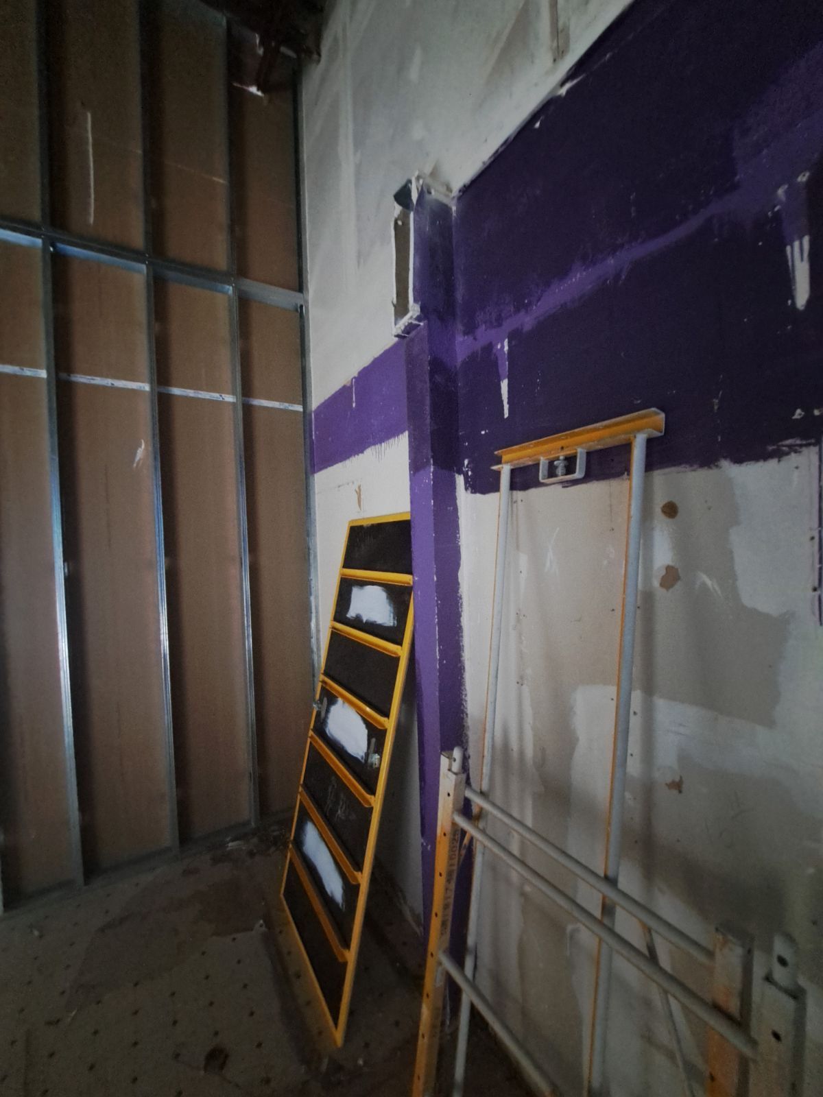 A room with a purple wall and a ladder on the floor