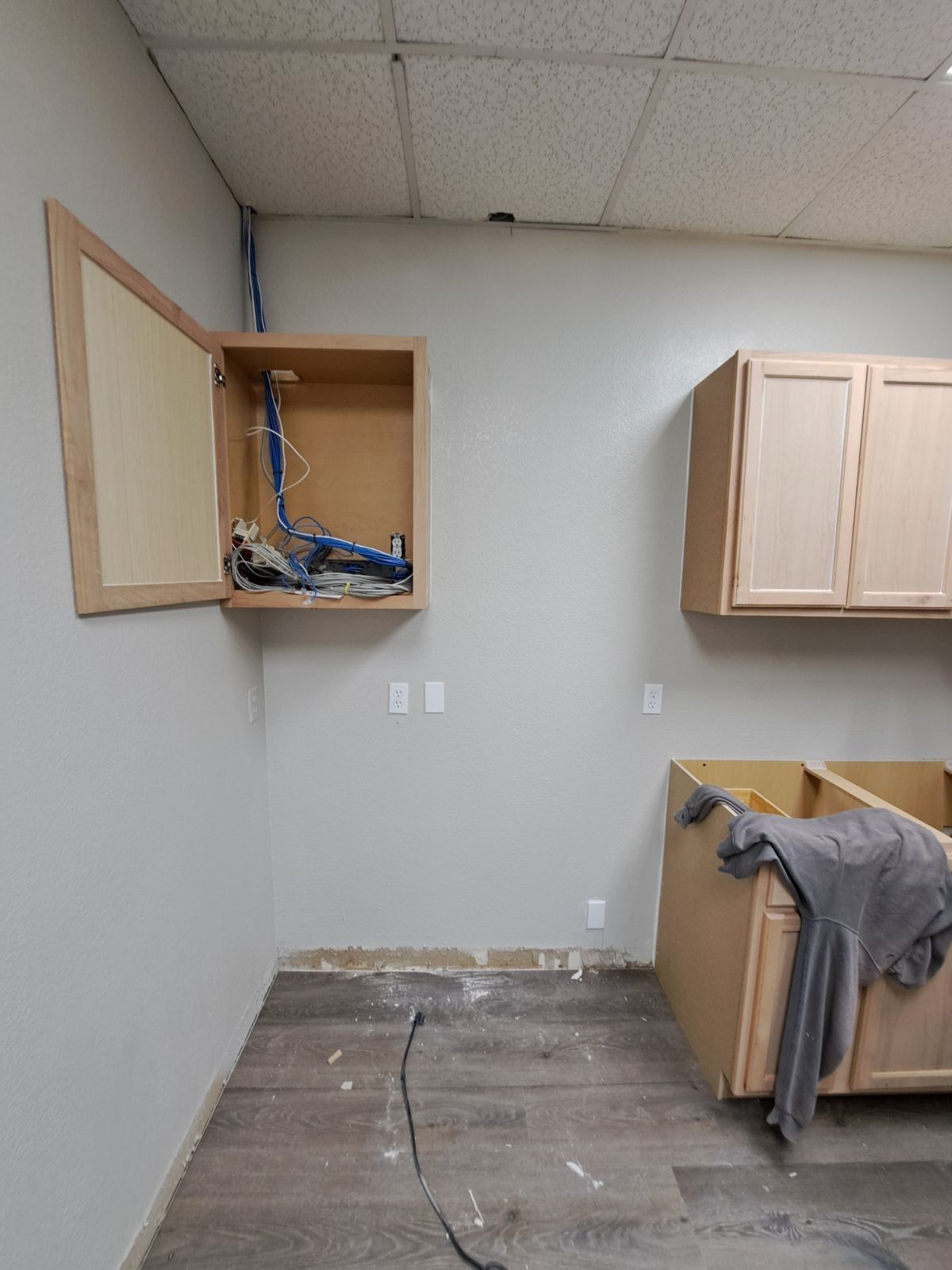 A room with wooden cabinets and a gray shirt on the floor.