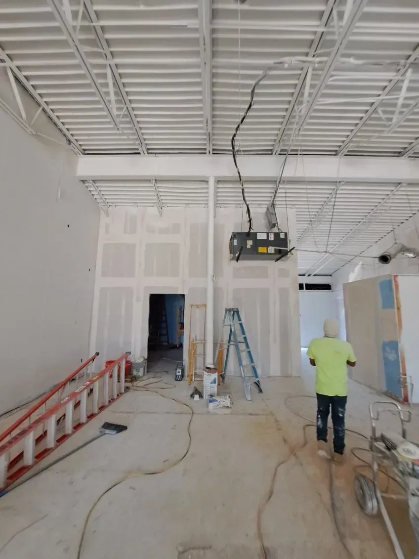 A man is standing on a ladder in an empty room.