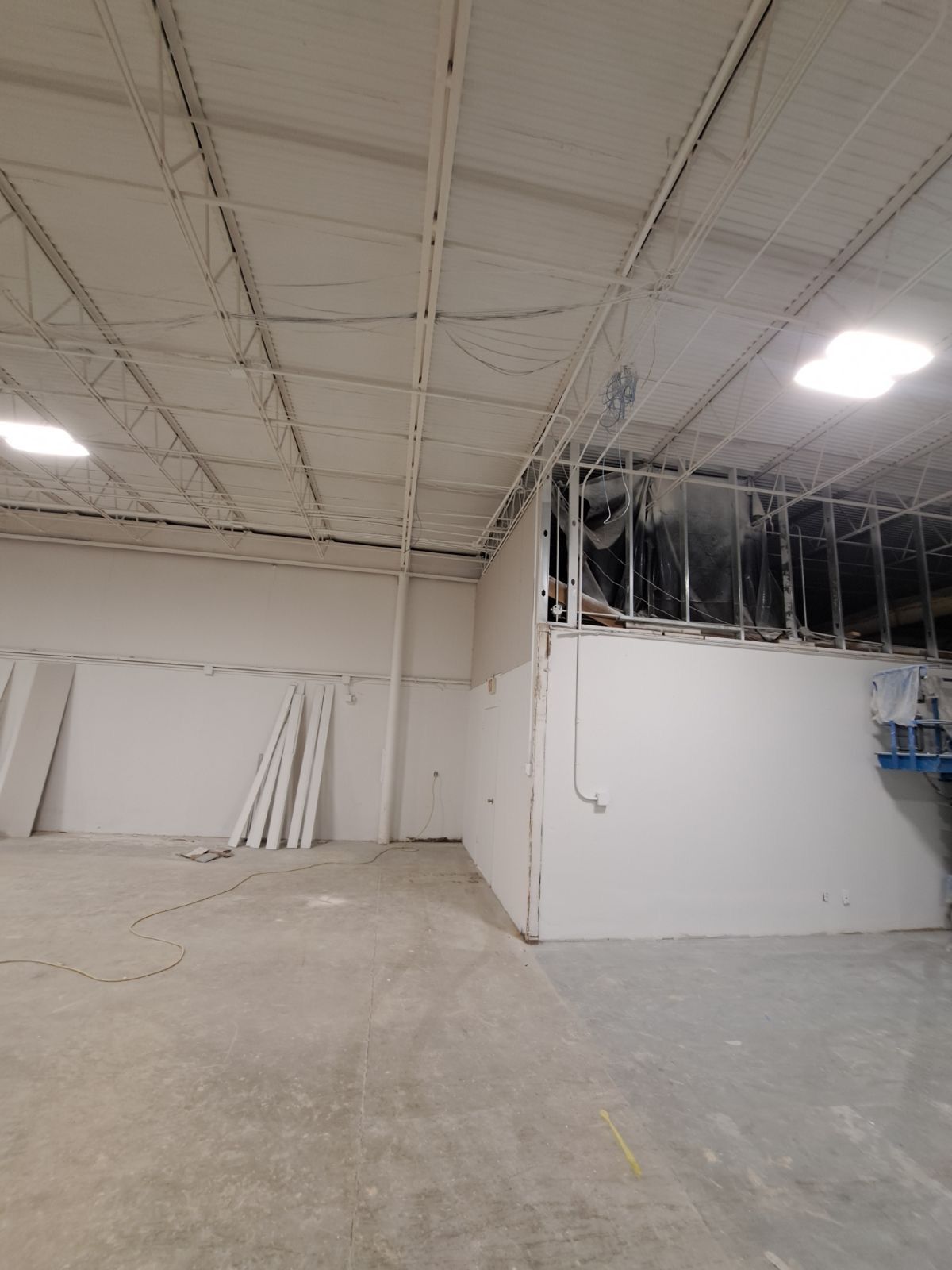 A large empty warehouse with white walls and a ceiling.