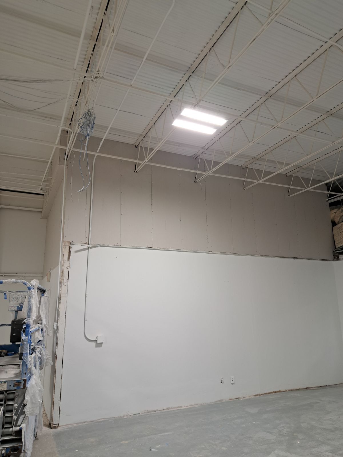 A large empty warehouse with white walls and a ceiling.