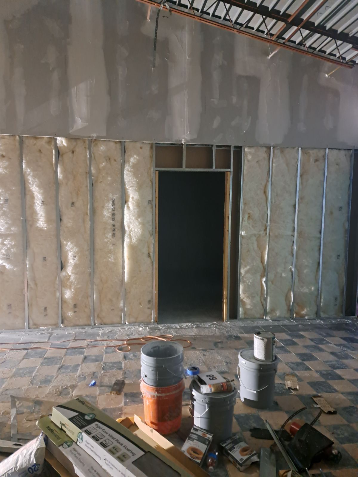 A room with a door and buckets of paint on the floor.