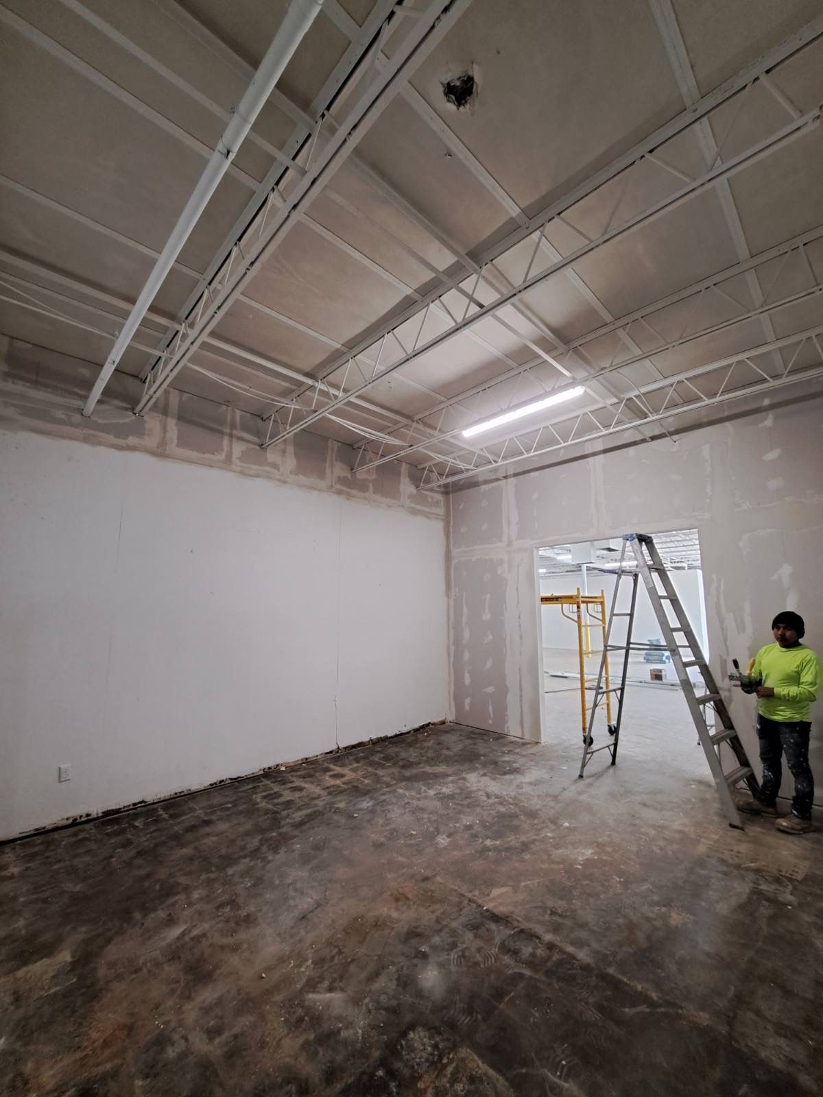 A man is standing in an empty room with a ladder.