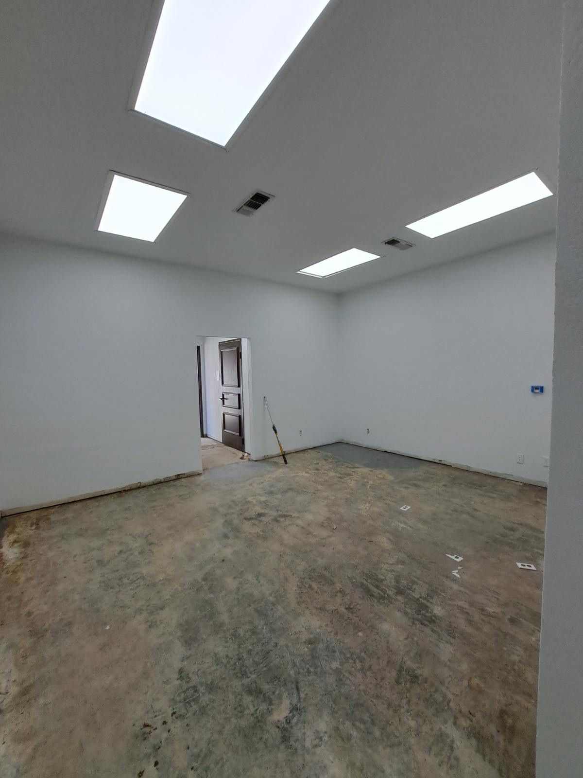 A large empty room with white walls and a concrete floor.