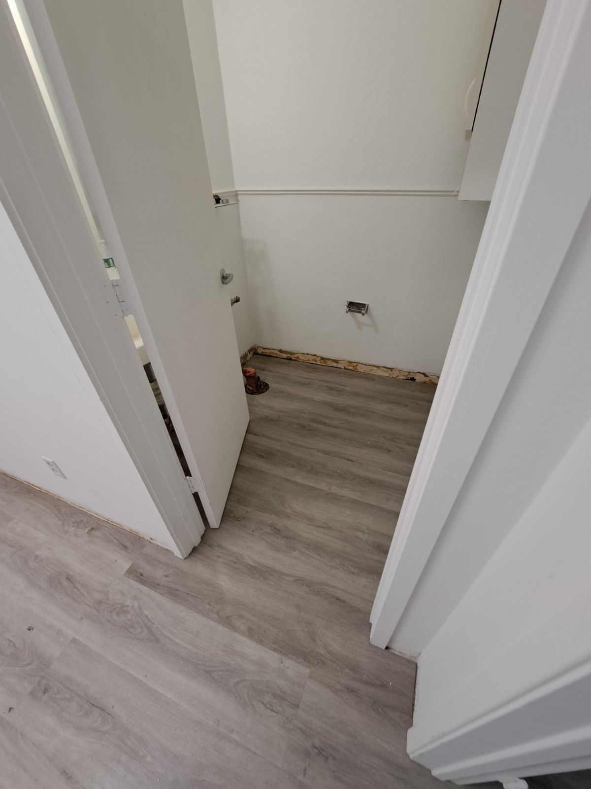 A hallway with a wooden floor and a white door.
