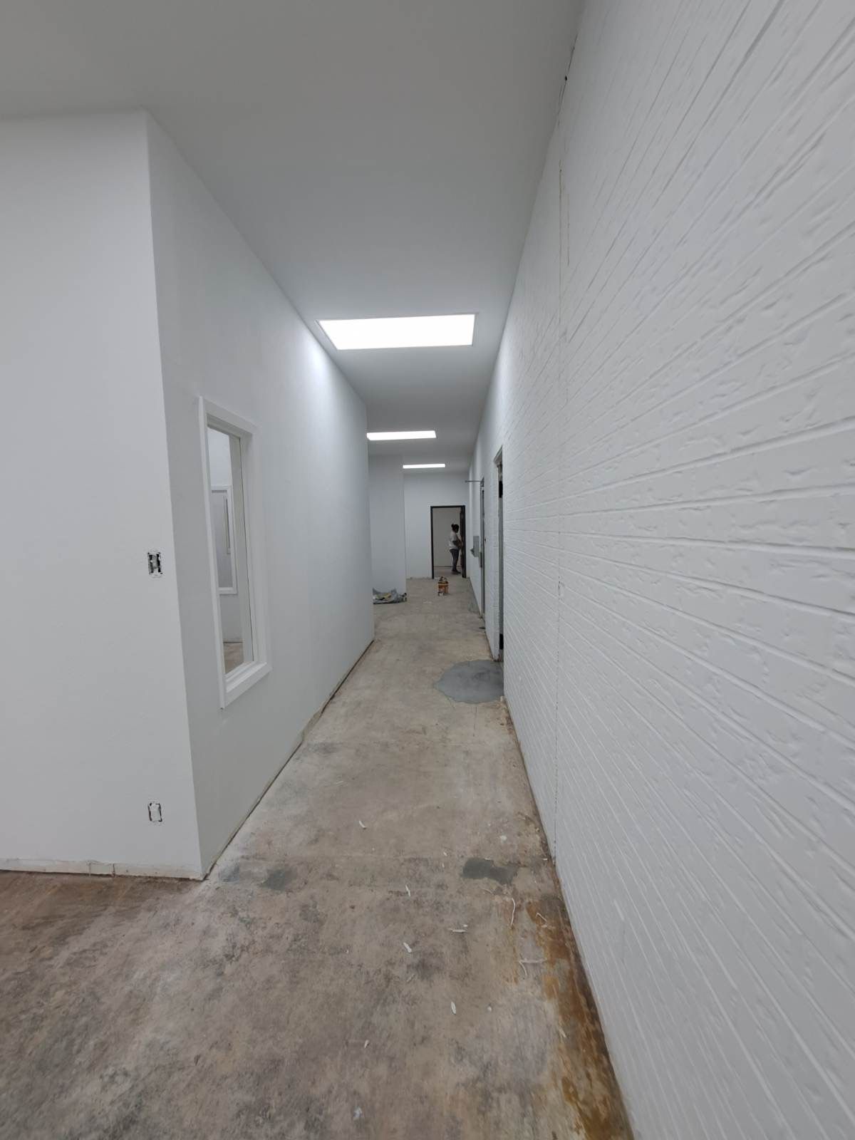 A long hallway with white brick walls and a concrete floor.