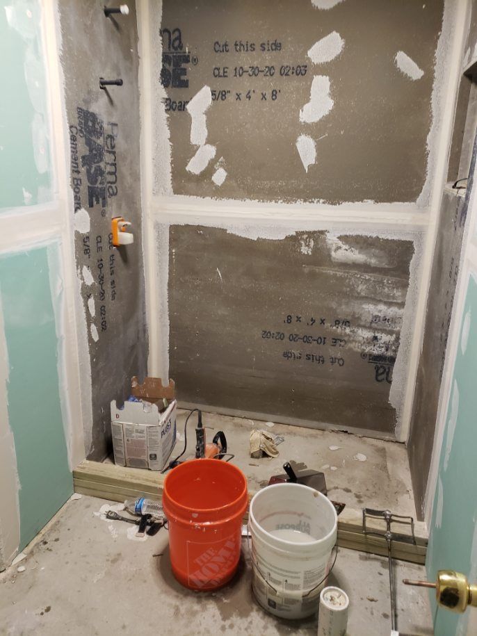 A bathroom under construction with buckets and tools on the floor.