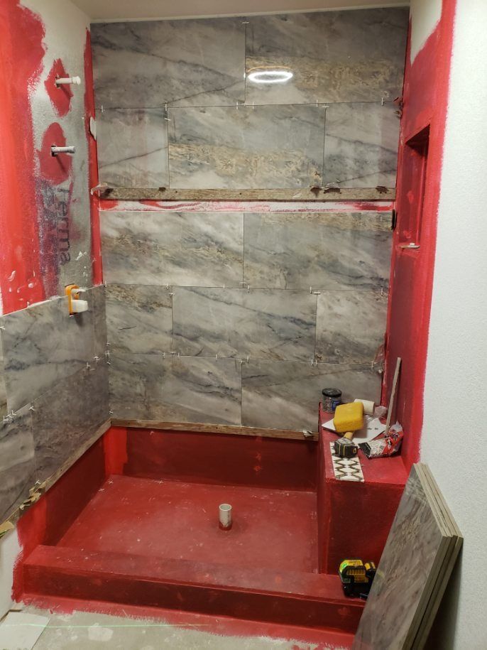 A bathroom under construction with red tiles and a red floor.