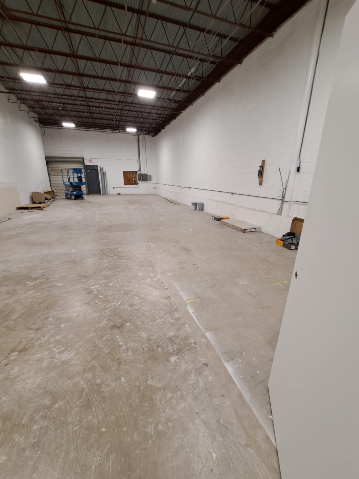 A large empty warehouse with white walls and a concrete floor.
