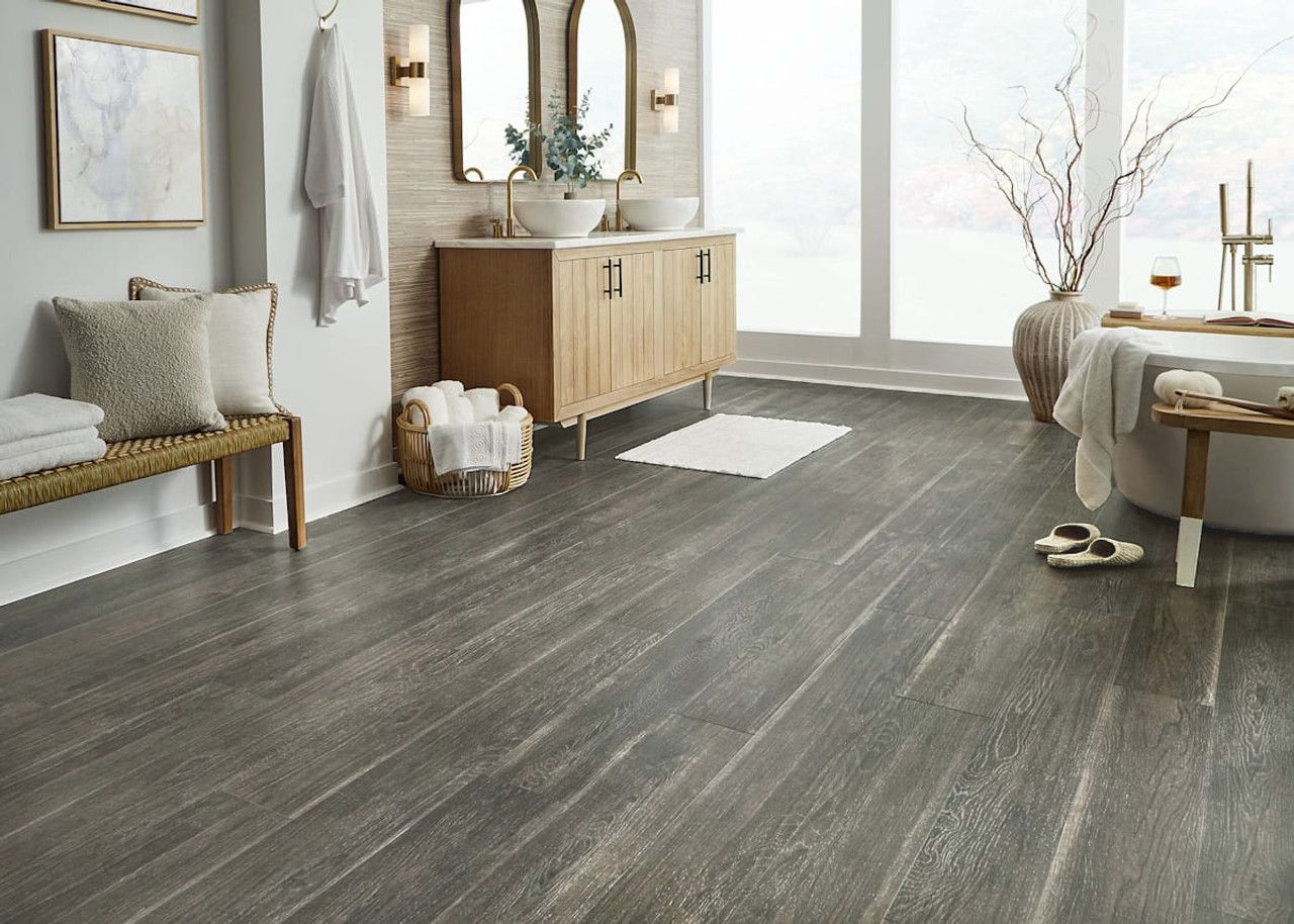 A bathroom with hardwood floors , a tub , sinks and mirrors.