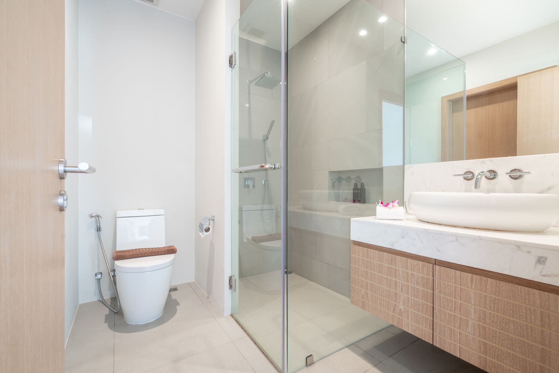 Modern bathroom with toilet, glass shower, and wood vanity with sink