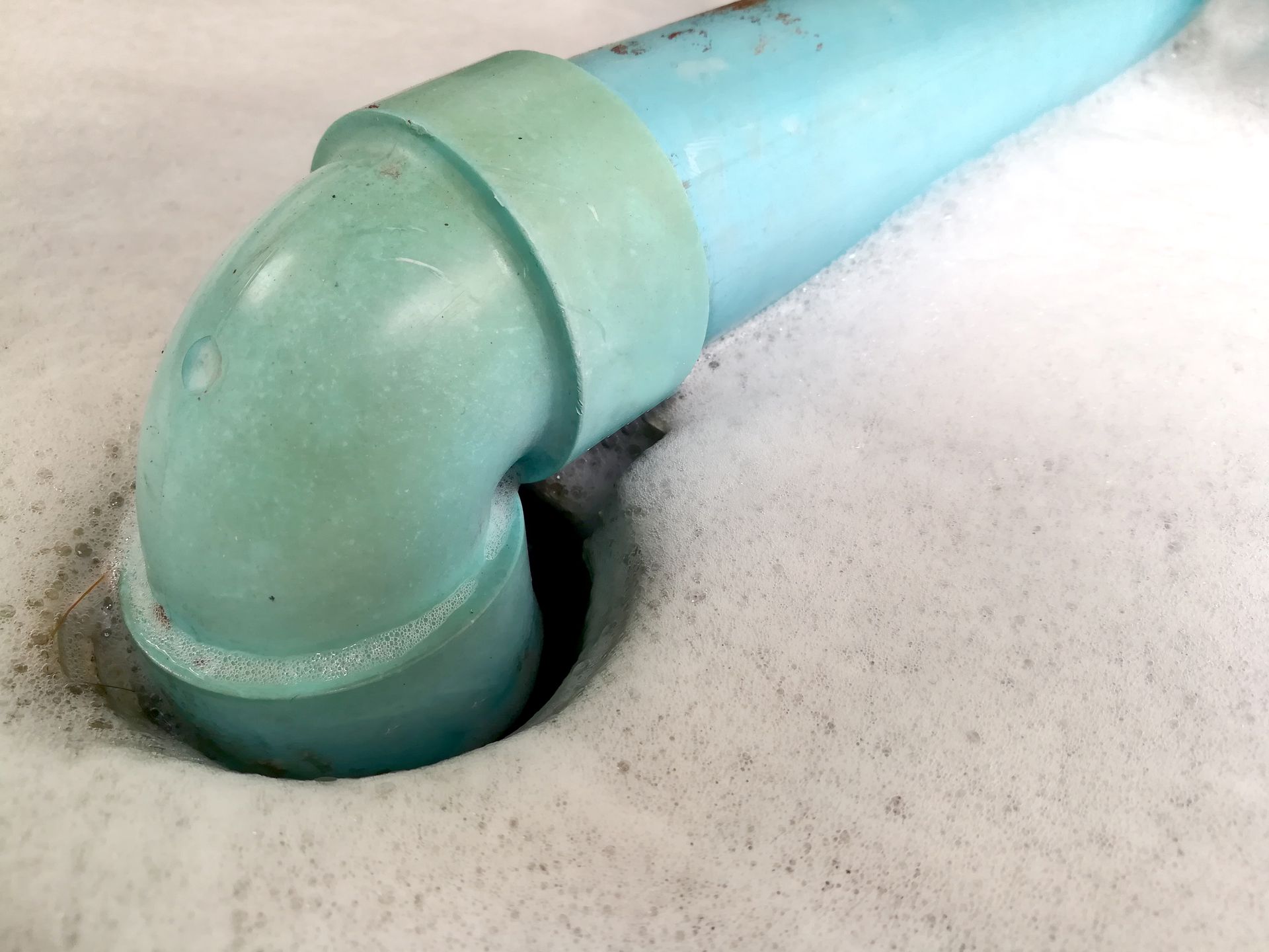 A close up of a blue pipe in a hole in the ground.