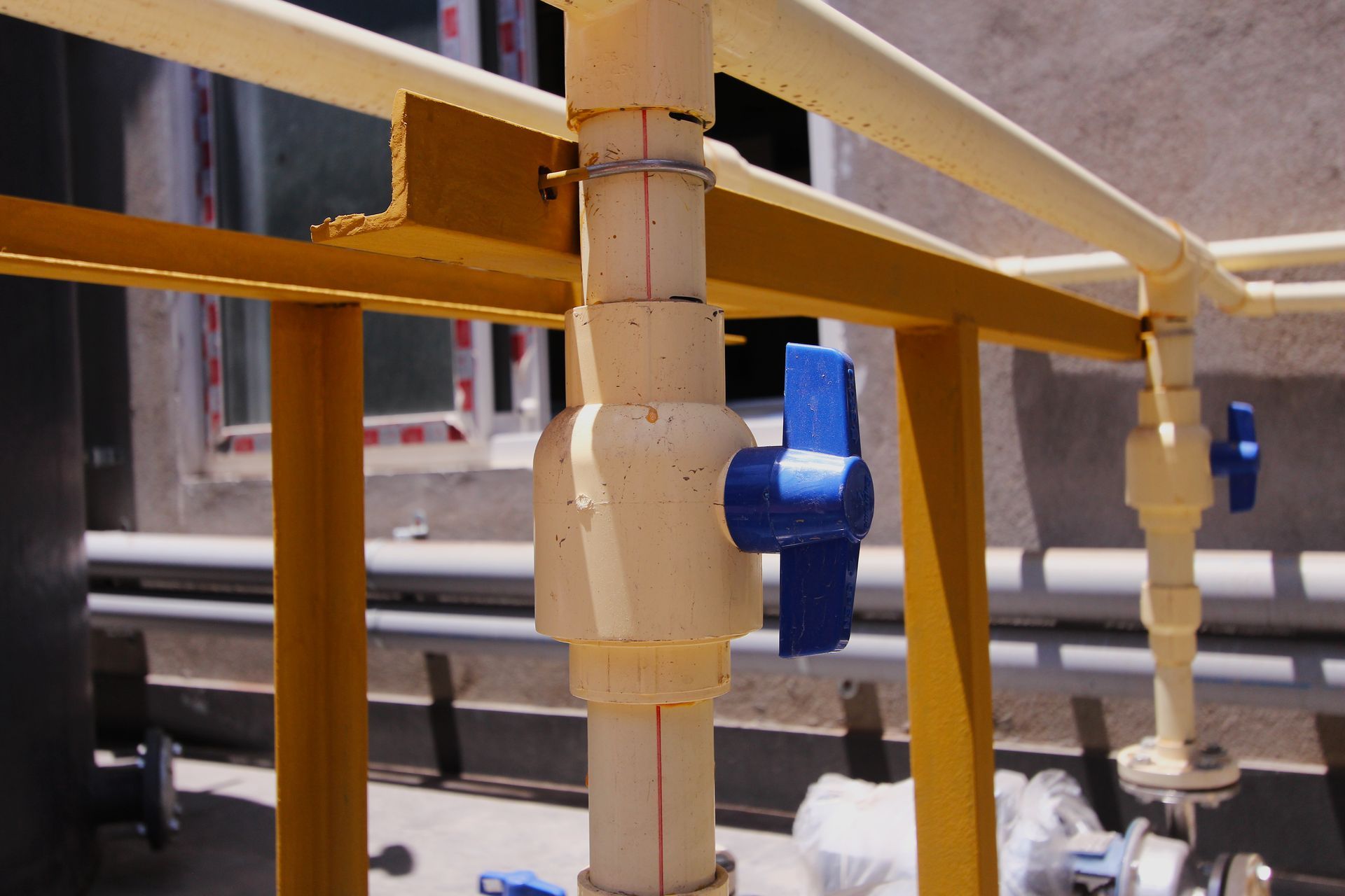 A blue valve is attached to a white pipe