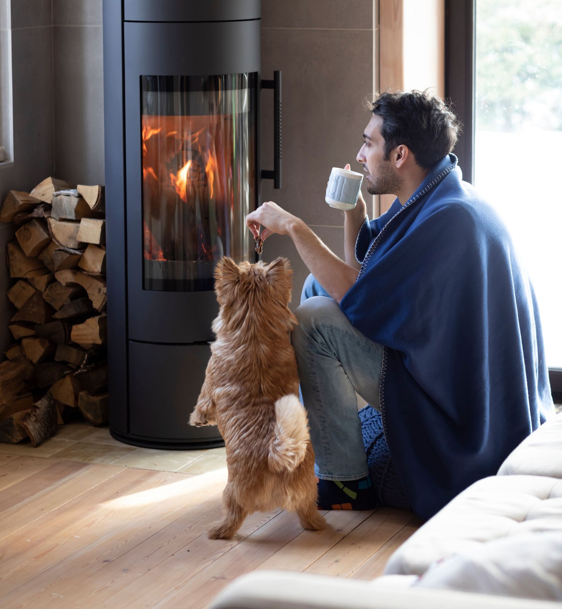 A man and a dog are sitting in front of a fireplace