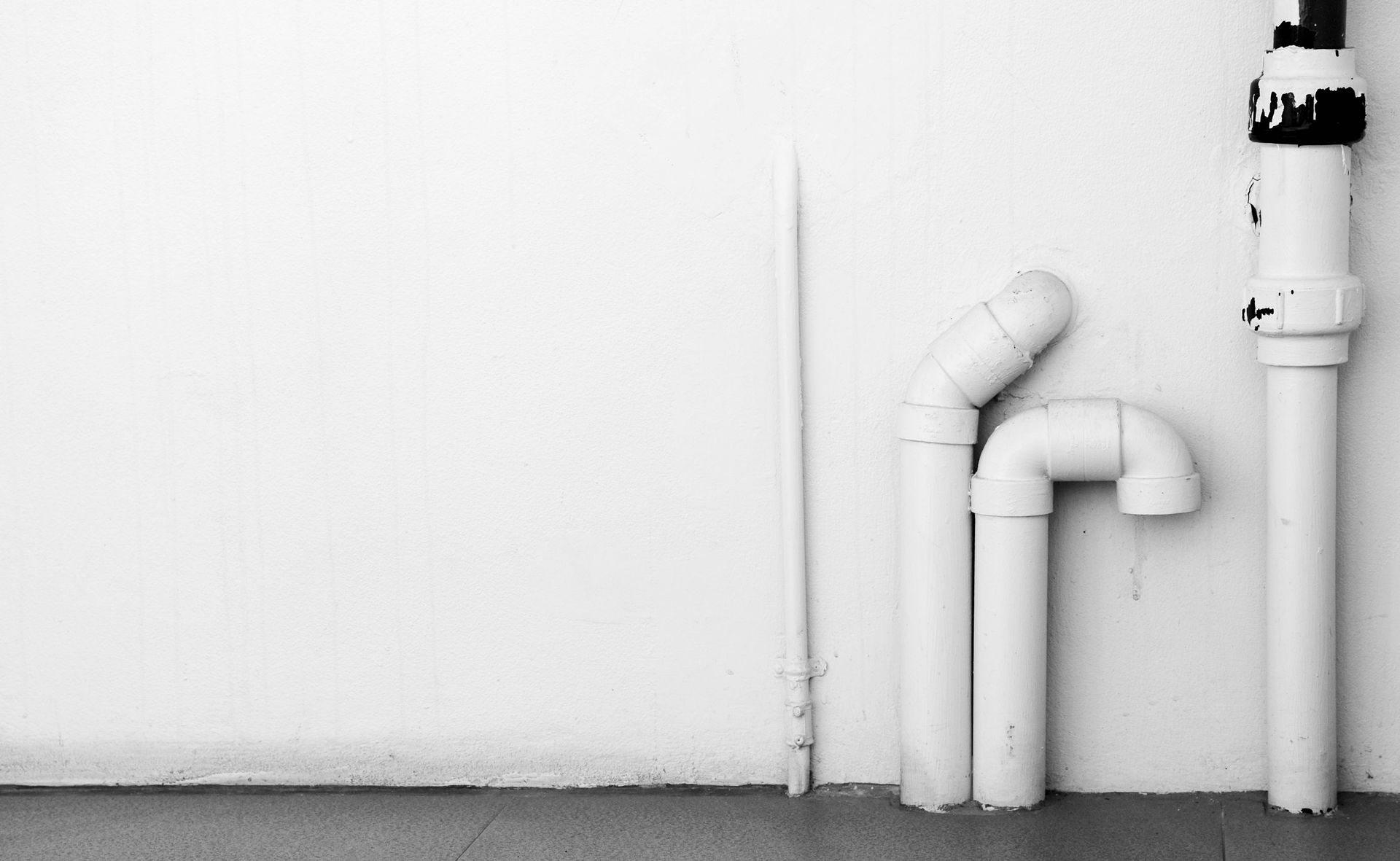 A black and white photo of white pipes against a white wall.
