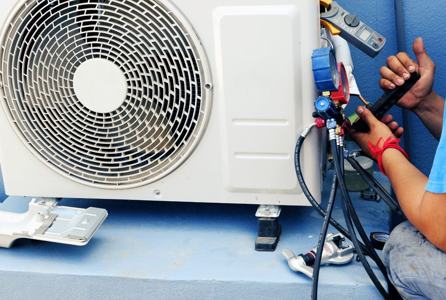 A man is working on an air conditioner outside of a building.