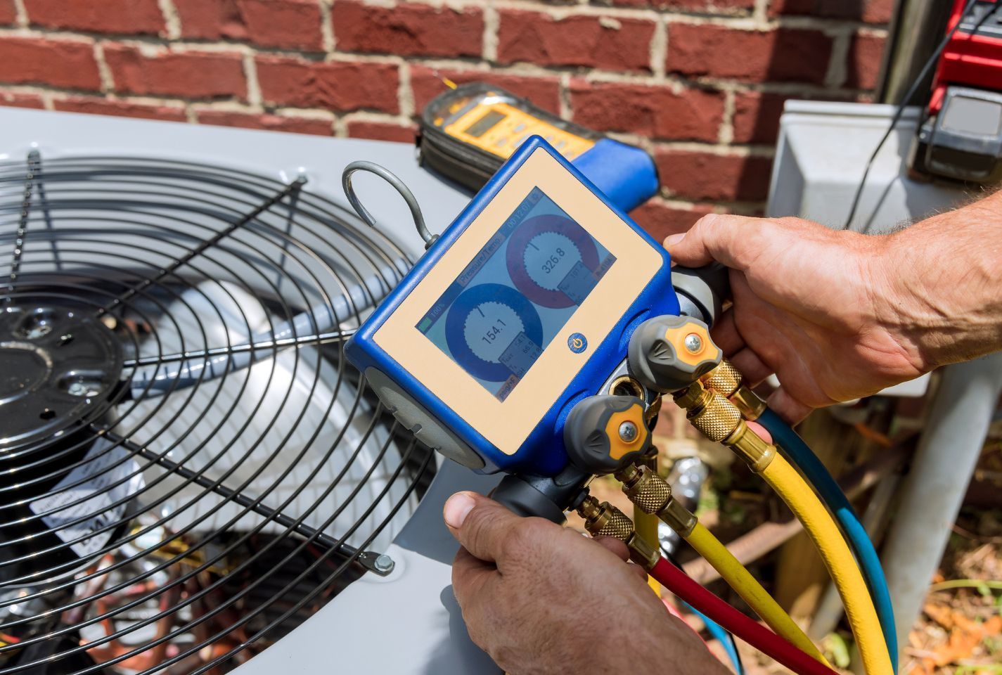 A man is working on an air conditioner outside of a brick building.