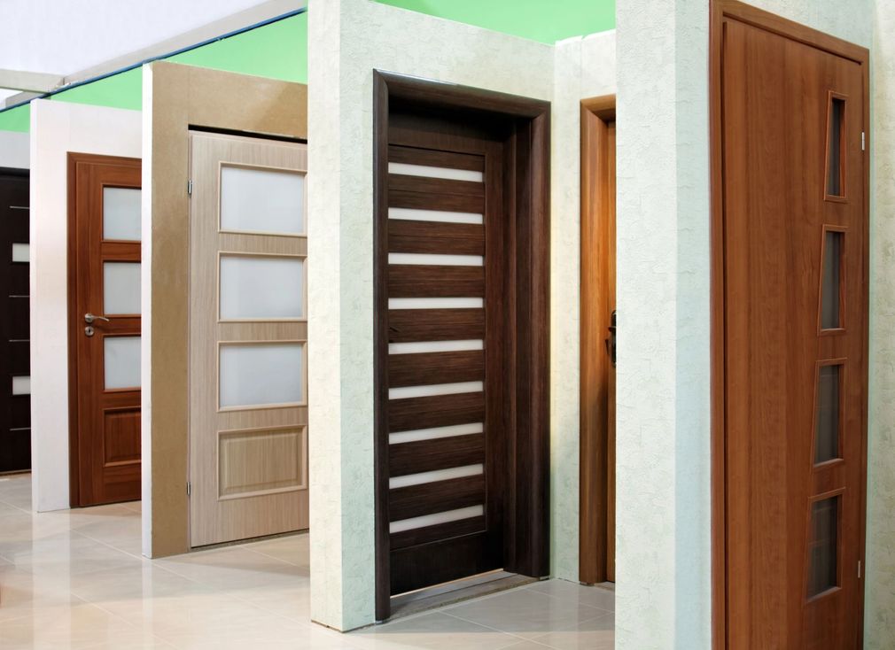 Una fila di porte interne moderne in diverse finiture e stili di legno in un corridoio