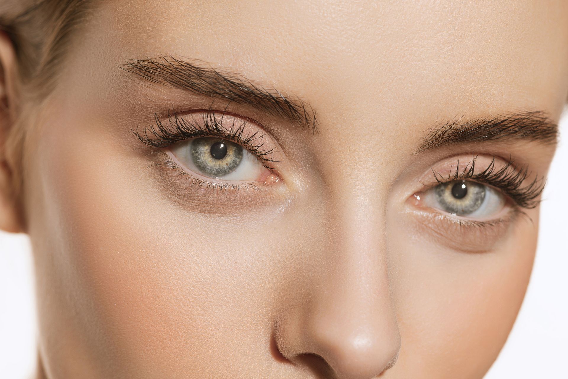 A close up of a woman 's face with blue eyes and long eyelashes.