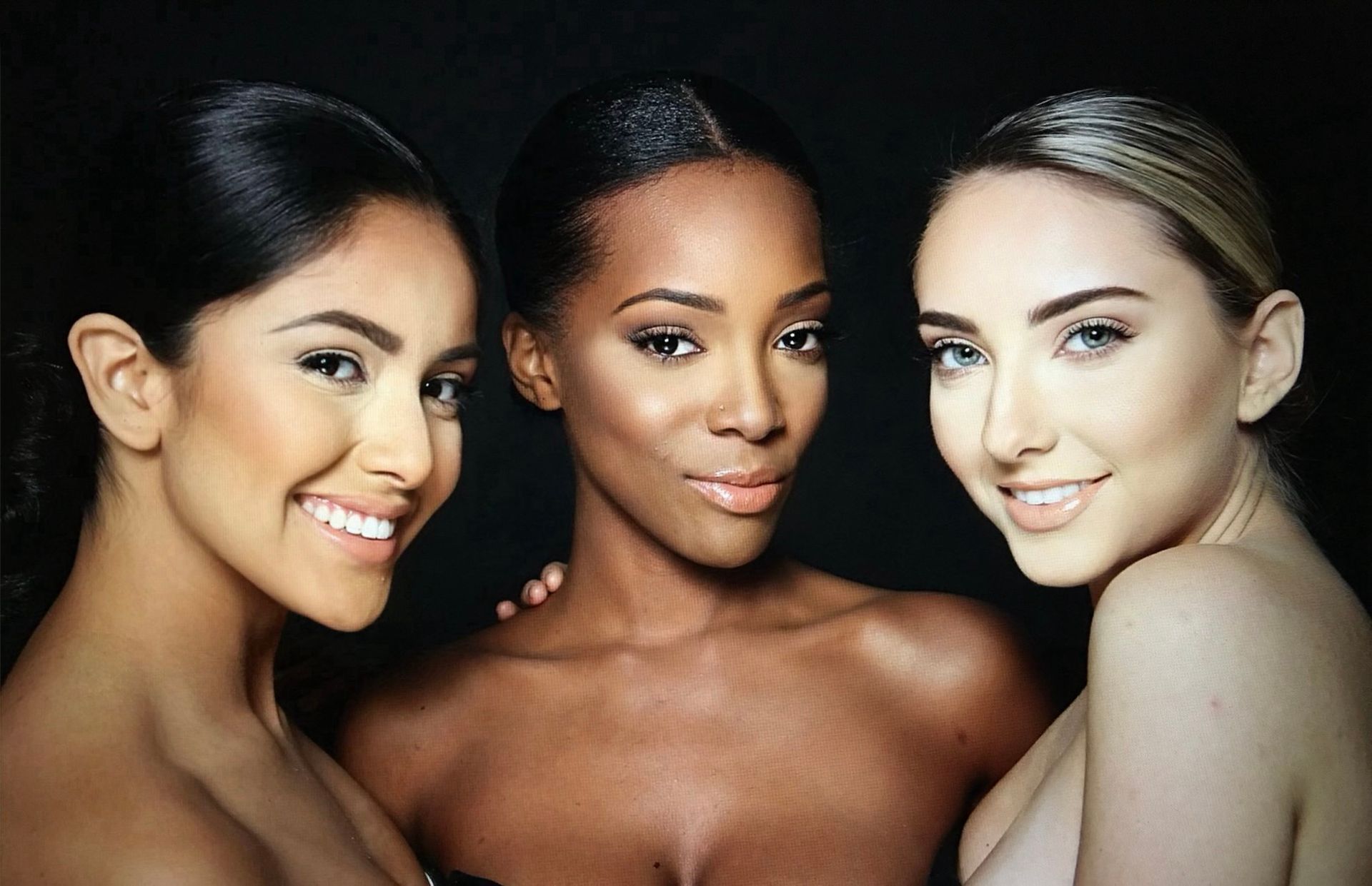 Three women are posing for a picture together and smiling for the camera.