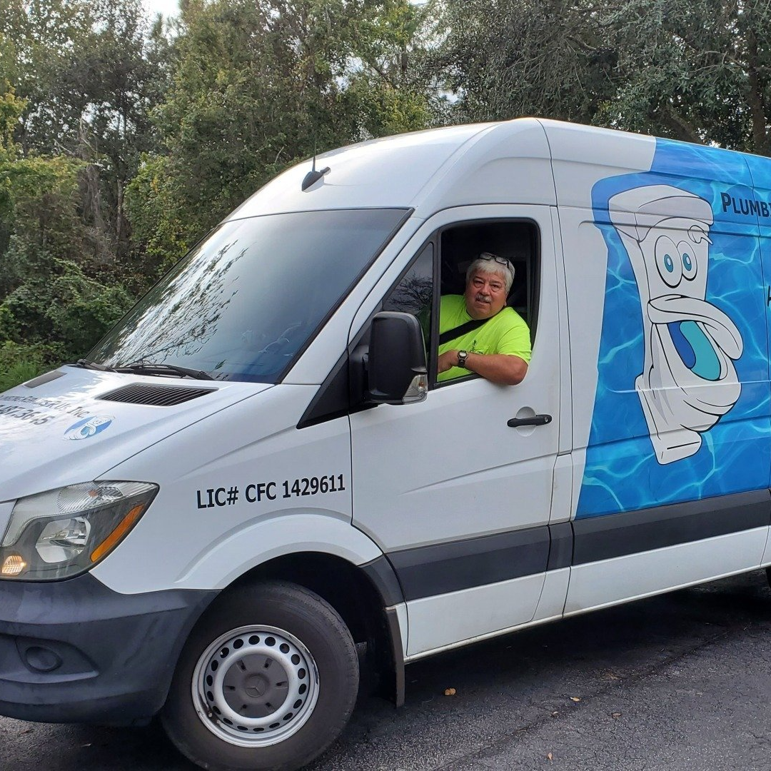 A man is sitting in the driver 's seat of a blue and white van.