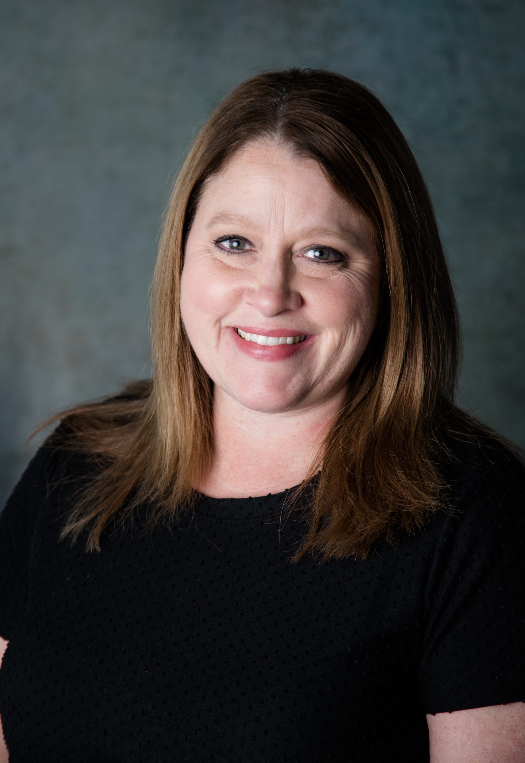 A woman in a black shirt is smiling for the camera.