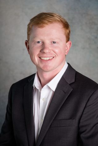 A man in a suit and white shirt is smiling for the camera.