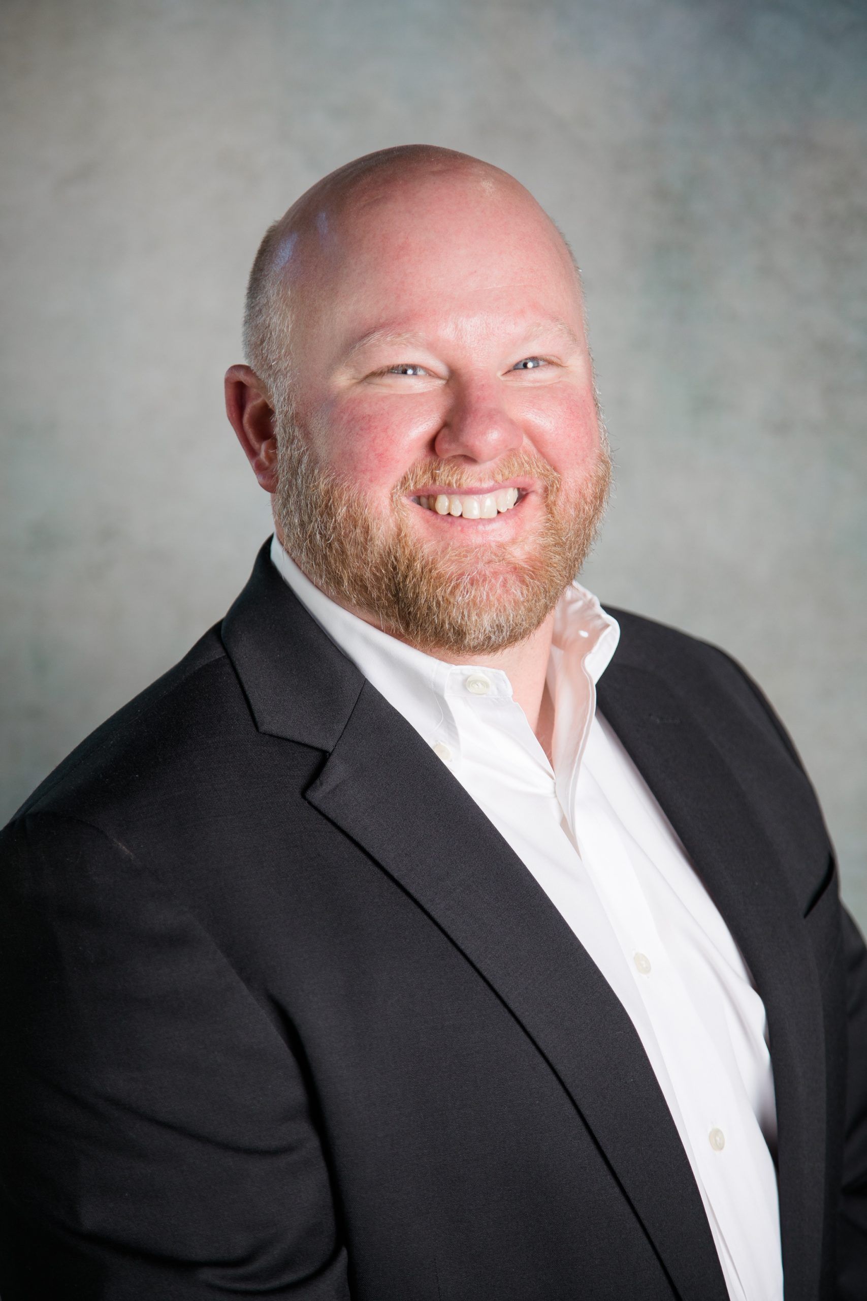 A man in a suit and white shirt is smiling for the camera.